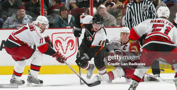 Mike Richards of the Philadelphia Flyers shoots the puck between Justin Williams and Rod Brind'Amour of the Carolina Hurricanes on December 15, 2007...