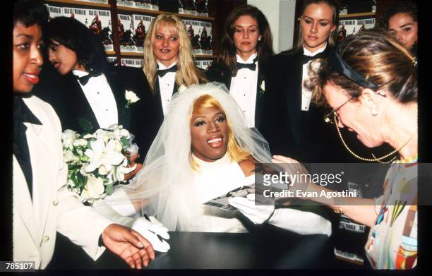 Dennis Rodman signs his autobiography August 21, 1996 in New York City. Rodman arrived in a horse-drawn carriage dressed in a wedding gown to launch...