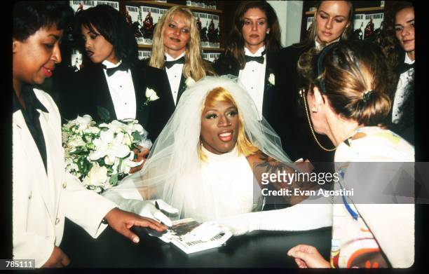 Dennis Rodman signs his autobiography August 21, 1996 in New York City. Rodman arrived in a horse-drawn carriage dressed in a wedding gown to launch...