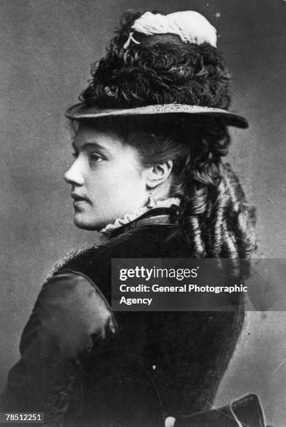 Young woman with her hair in ringlets and wearing bell-shaped earrings and a hat, circa 1855.