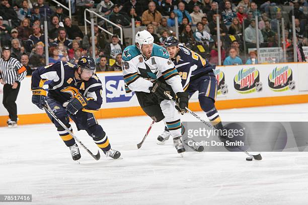 Joe Thornton of the San Jose Sharks skates by Paul Gaustad and Jaroslav Spacek of the Buffalo Sabres during an NHL game on December 8, 2007 at HP...