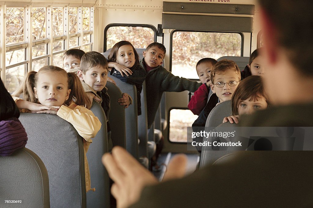 Adult talking to children on school bus