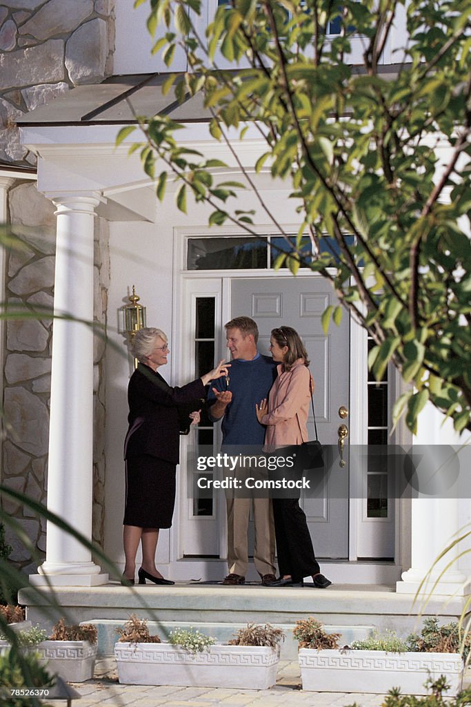 Real estate agent giving keys to couple