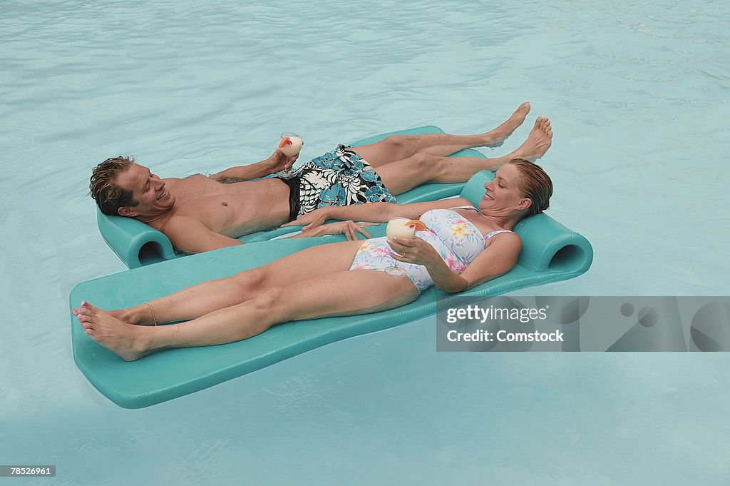 Couple in pool with tropical drinks