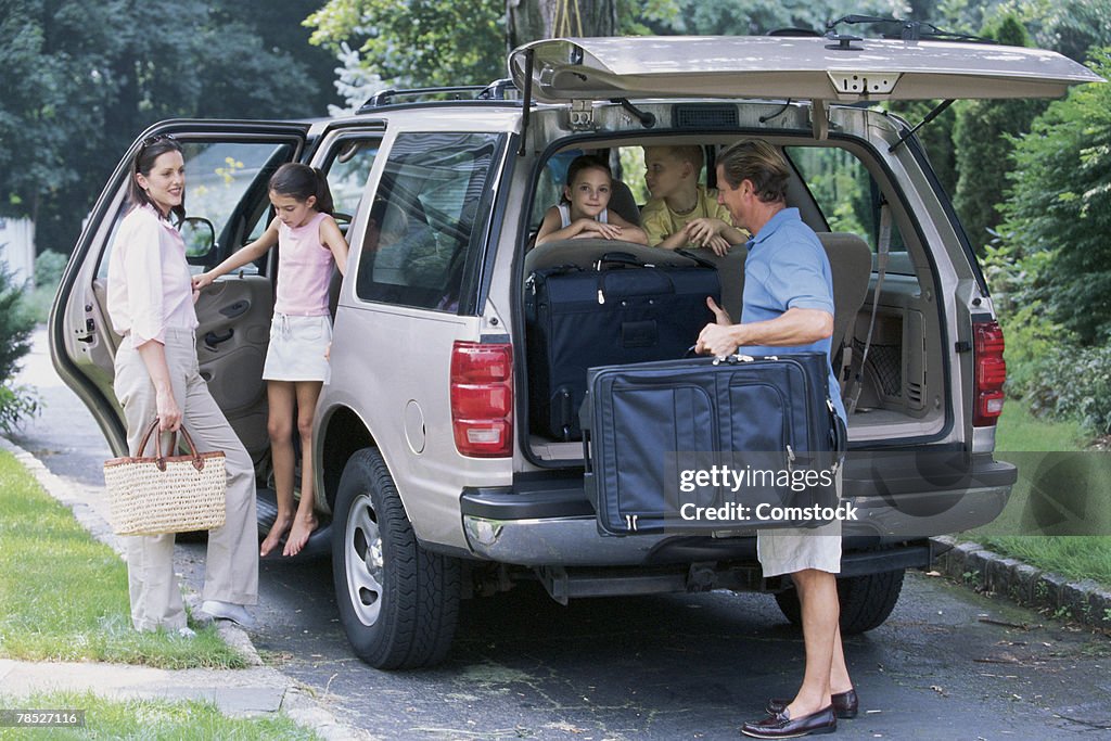Family packing suitcases into SUV