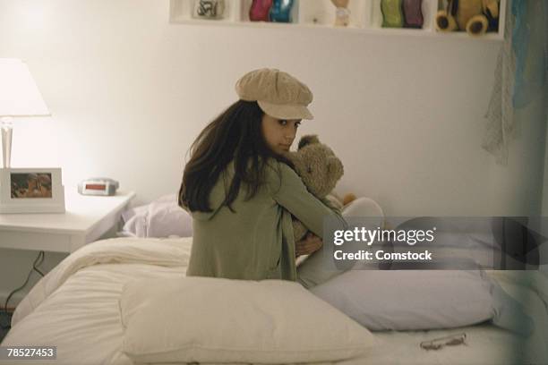 teenager sitting on bed holding teddy bear - kuscheldecke stock-fotos und bilder