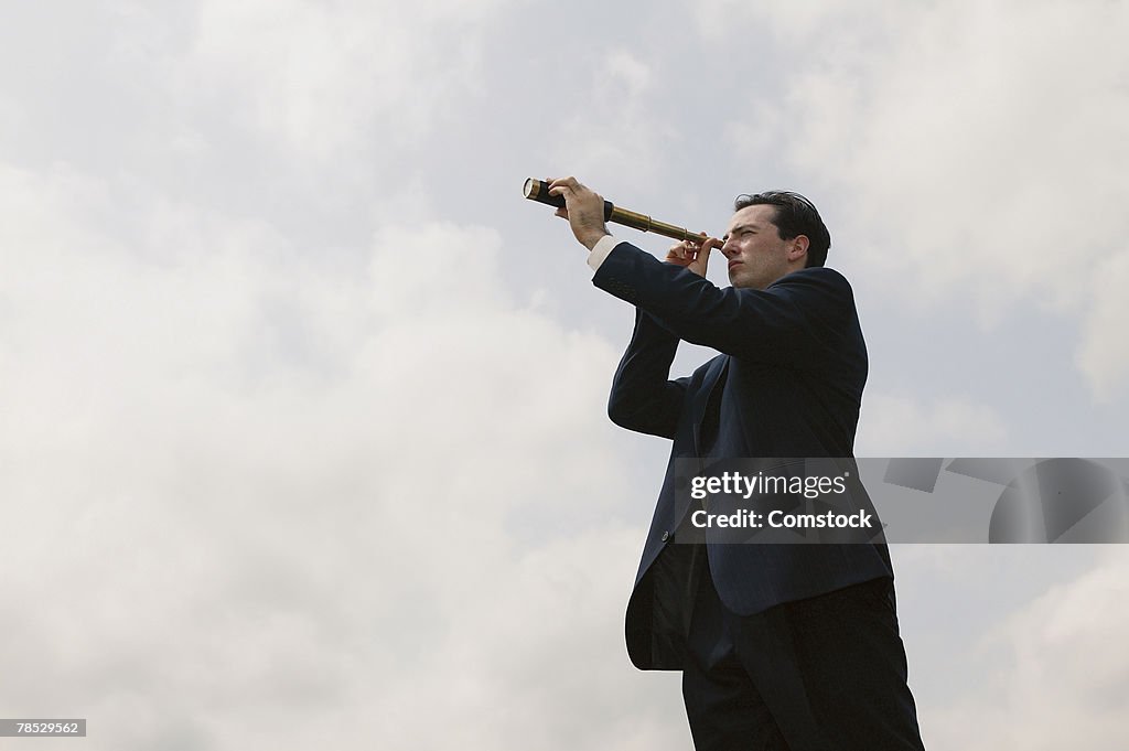 Businessman looking through spyglass