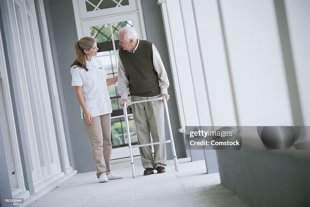 Nurse helping man with walker