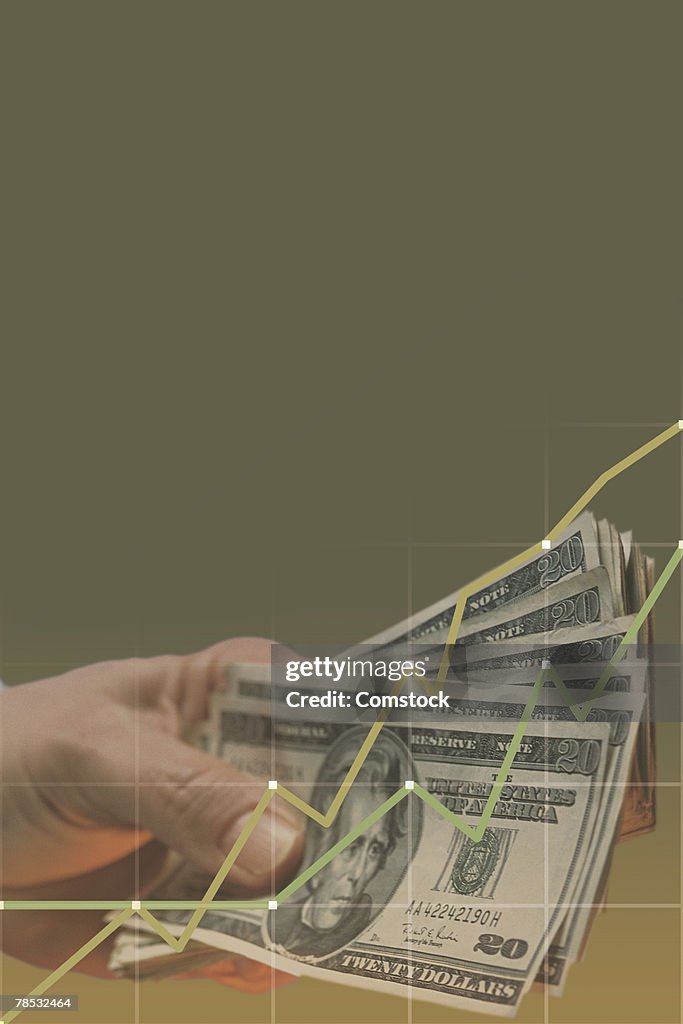 Composite of hand holding money with graph