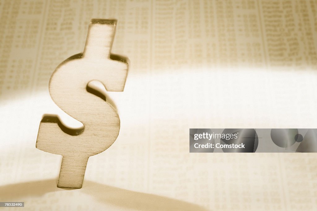 Dollar symbol on top of newspaper stock quotes