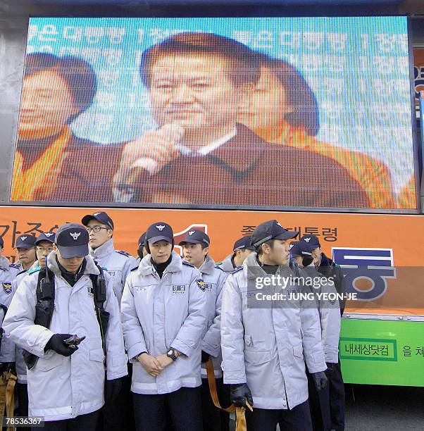 Policemen stand in front of a big screen showing Chung Dong-Young, South Korean presidential candidate for the pro-government United New Democratic...