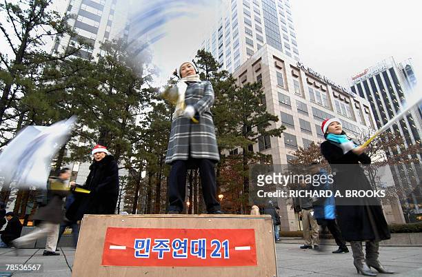 Group of women wearing Santa Claus hats waves South Korean and political flags calling on the country's liberal parties to unite as one, during a...