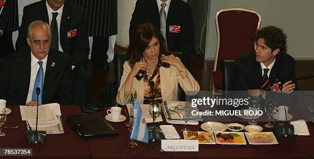 Argentina's president Cristina Fernandez de Kirchner straightens her scarf next to her Foreign minister Jorge Taiana and Economy minister Martin...
