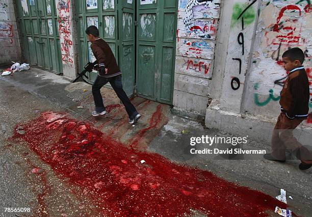 Palestinian boys pass a stream of blood from sheep slaughtered inside a home for Eid al-Adha in al-Azza refugee camp December 19, 2007 in Bethlehem...