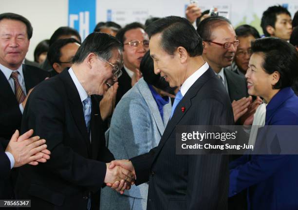 Lee Myung-Bak of the conservative main opposition Grand National Party shakes hands with his party members during their applause after he is declared...