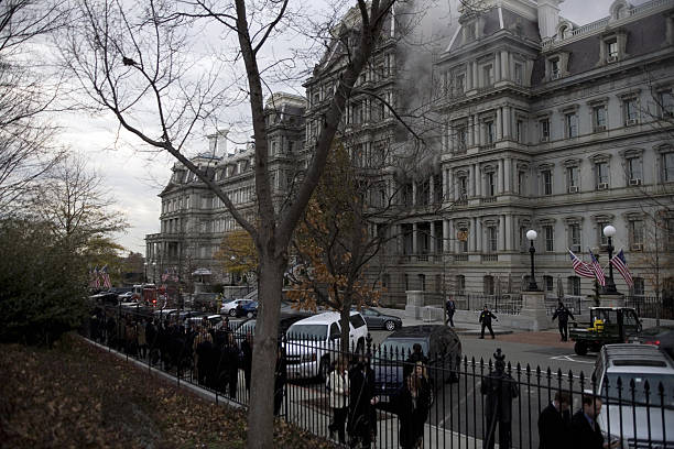 Smoke billows out the windows while personnel are evacuated as a fire rages at the Eisenhower Executive Office Building next the White House in...