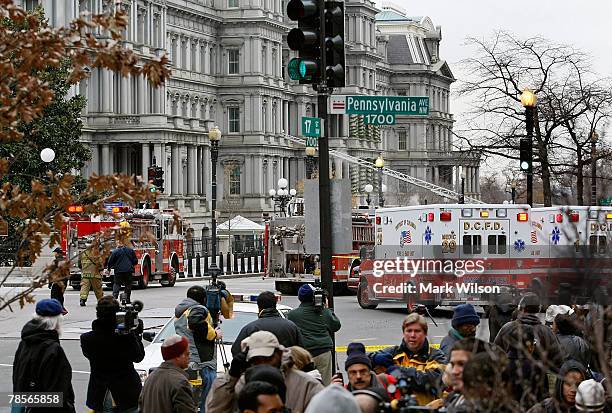 People watch as fire trucks and emergency vehicles surround the Old Executive Office Building near the White House to extinguish a fire December 19,...