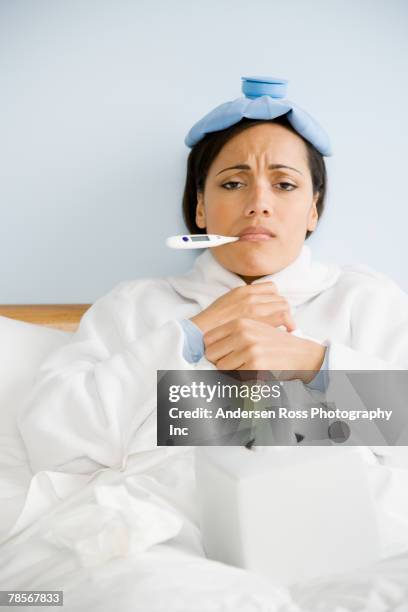 sick african american woman taking temperature - junge frau bett sitzen blick in die kamera stock-fotos und bilder