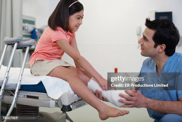 hispanic medical professional examining girl's cast - bare feet kneeling girl stock pictures, royalty-free photos & images