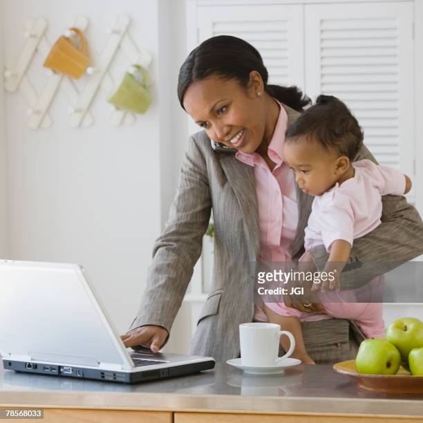 african american mother working at holding baby - working mom stock pictures, royalty-free photos & images