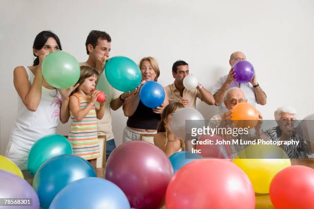 multi-generational hispanic family blowing up balloons - jonge senioren in groep stockfoto's en -beelden