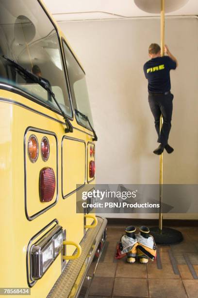 male firefighter sliding down pole - firefighter boot stock pictures, royalty-free photos & images