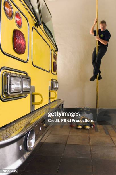 male firefighter sliding down pole - fire station pole stock pictures, royalty-free photos & images