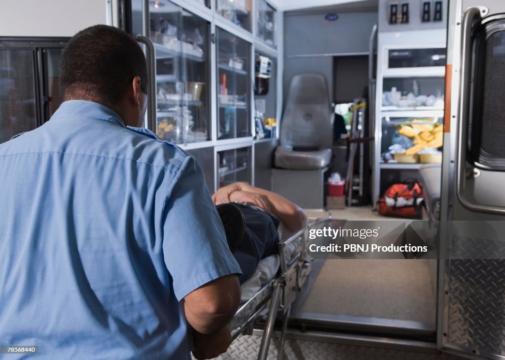 Asian male paramedic loading patient into ambulance