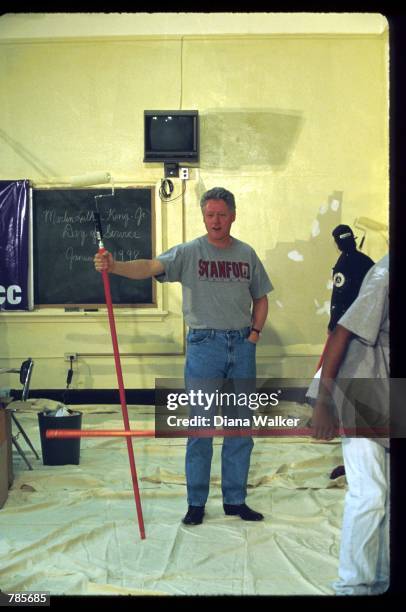 President Bill Clinton stands with a roller brush January 19, 1998 in Washington, DC. Clinton joined sixty-five AmeriCorps members and three hundred...