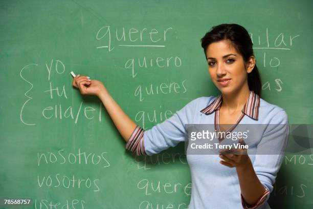 hispanic female teacher in front of blackboard - mensch kreide stock-fotos und bilder