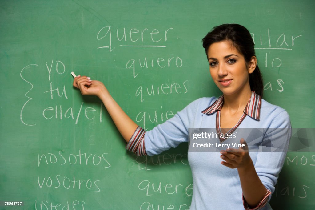 Hispanic female teacher in front of blackboard