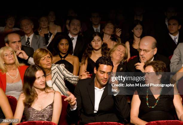 hispanic man talking on cell phone in theatre - egoismus stock-fotos und bilder