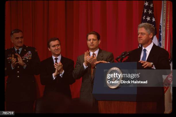 President Bill Clinton stands at a podium while Vice President Al Gore, General Henry Shelton and Secretary of Defense William Cohen clap February...