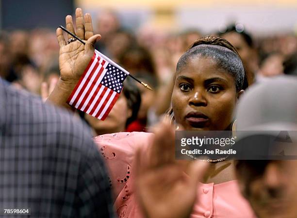 Paulette Simeanil originally from Haiti raises her arm during the naturalization ceremony conducted by the Immigration and Naturalization Service at...