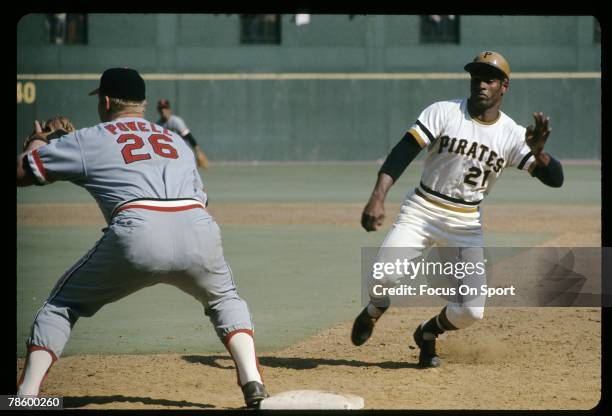 Outfielder Roberto Clemente of the Pittsburgh Pitrates slides back into first base as Baltimore Orioles first baseman Boog Powell waits on the throw...