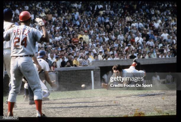 1960s: Outfielder Pete Rose of the Cincinnati Reds slides head first at home plate against the Chicago Cubs during a MLB baseball game circa late...