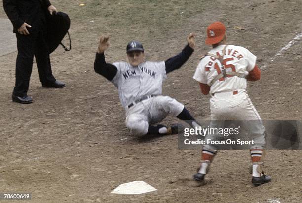 Roger Maris of the New York Yankees slides in safe at home plate as catcher Tim McCarver of the St. Louis Cardinals looks on, during the World Series...