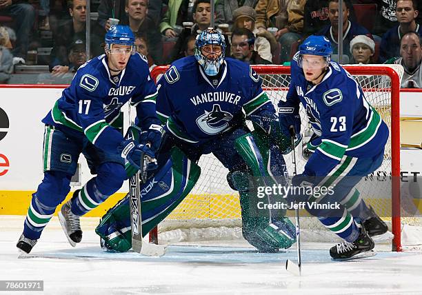 Goaltender Roberto Luongo, Ryan Kesler and Alexander Edler of the Vancouver Canucks look for a rebound during their game against the Dallas Stars at...