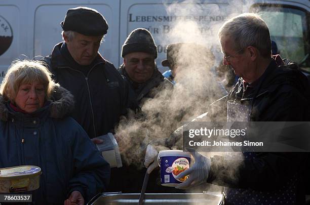 Ulli , member of charitable society Muenchner Tafel distributes a christmas dinner to poor people outside Capuchin Convent on December 21, 2007 in...