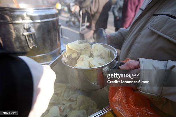 Members of charitable society Muenchner Tafel distribute hot dishes to poor people outside Capuchin Convent on December 21, 2007 in Munich, Germany....