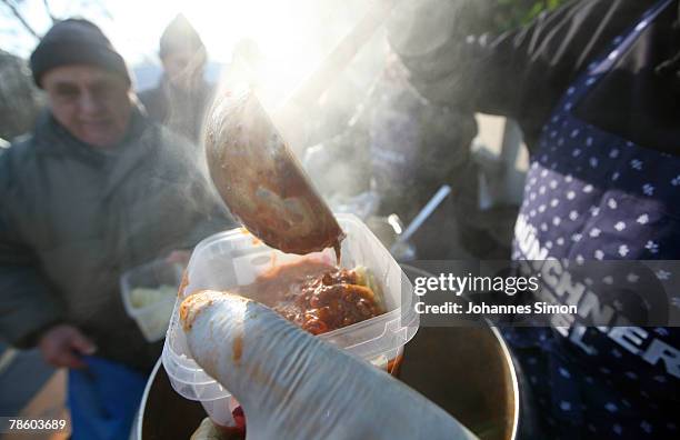 Members of charitable society Muenchner Tafel distribute hot dishes to poor people outside Capuchin Convent on December 21, 2007 in Munich, Germany....