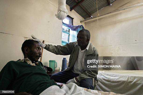 By LUCIE PEYTERMANN Charles Kibe , a volunteer who works with HIV/AIDS infected people in the Korogocho slum in eastern Nairobi, attends a patient at...