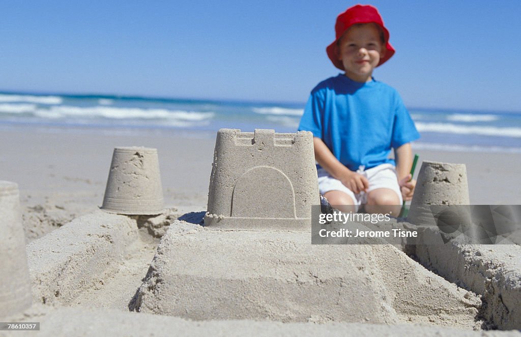 Boy with sand castle on beach