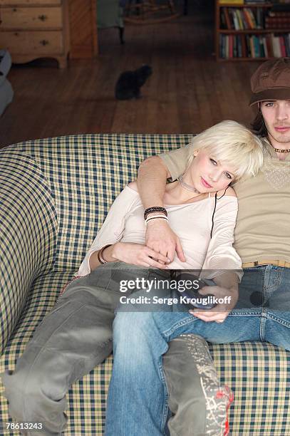 couple listening to headphones on couch - personal cassette player stockfoto's en -beelden