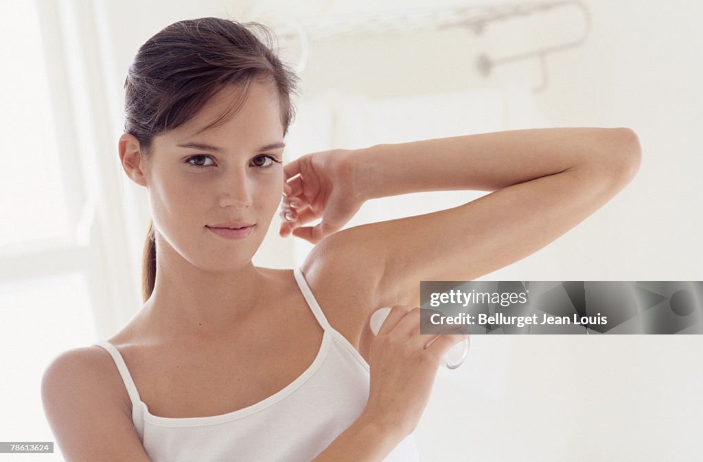 Woman applying deodorant to underarm