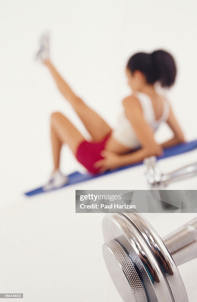 Woman stretching near weights