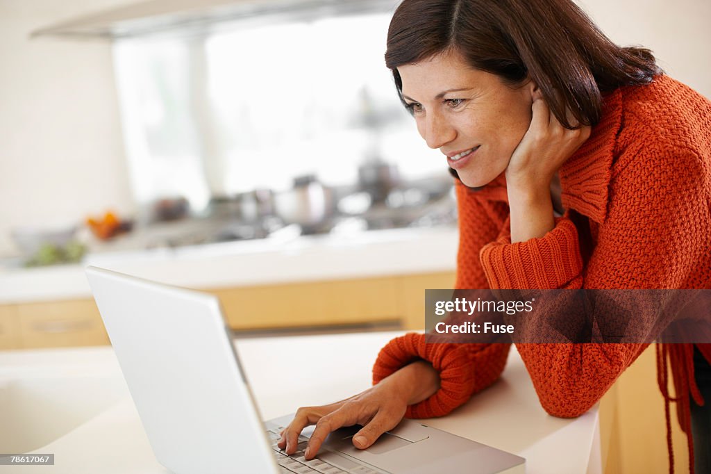 Woman Using Laptop in Kitchen