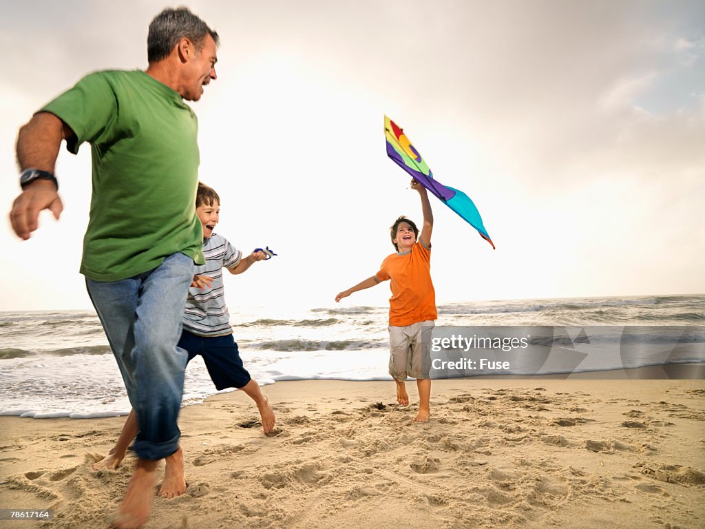 Father and Two Sons on Beach Flying Kite