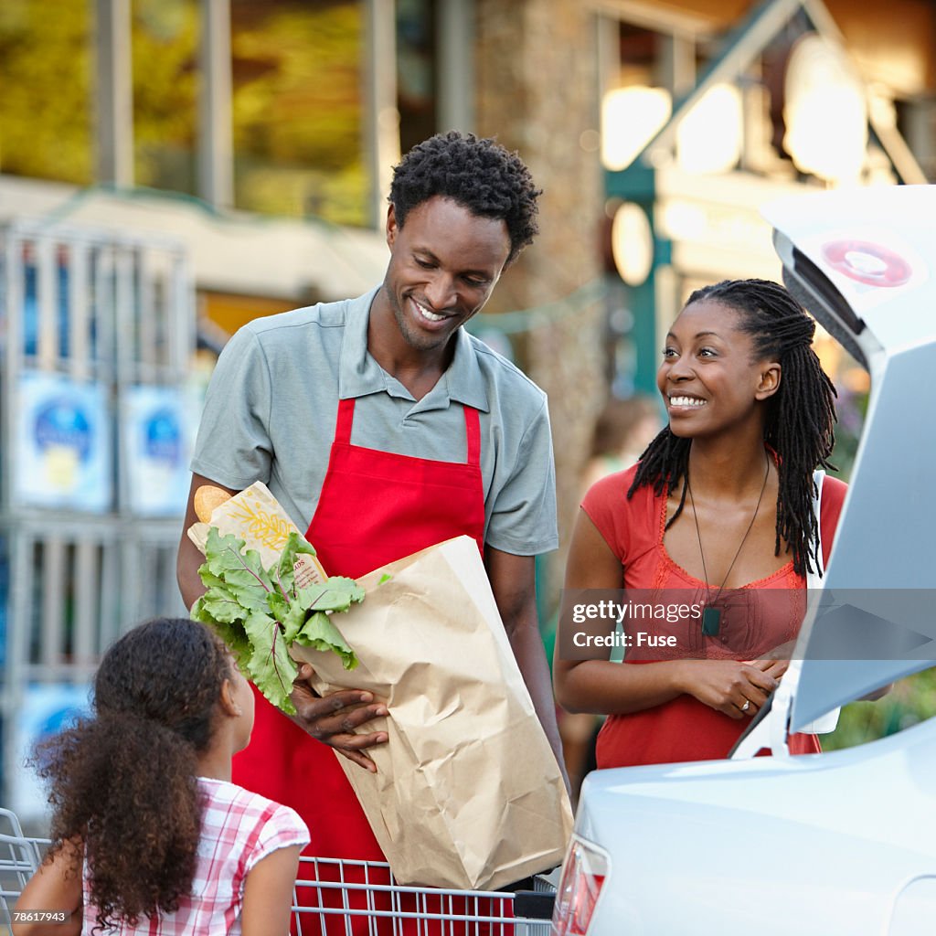 Grocer Helping Mother and Daughter to Car with Groceries