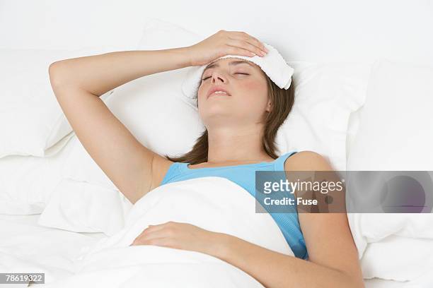 young woman with fever - washcloth stock-fotos und bilder